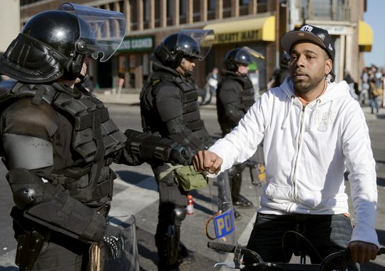 Man fist bumps law enforcement personnel during Baltimore protests. Courtesy of USAtoday.com 