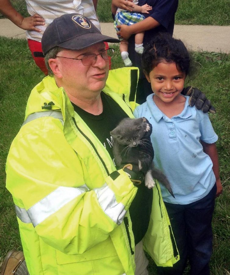 In this May 26, 2015 photo, Lancaster Township Fire Department Deputy Fire Chief  Glenn Usdin, left, holds the kitten that was rescued with the help of 6-year-old Janeysha Cruz in Lancaster, Pa. Firefighters were too big to rescue the kitten from a storm drain, so with the permission of Cruzs mother, they lowered the kindergartner nearly 3 feet into the storm drain to coax the kitten out. (Brett J. Fassnacht/Lancaster Township Fire Department via AP)