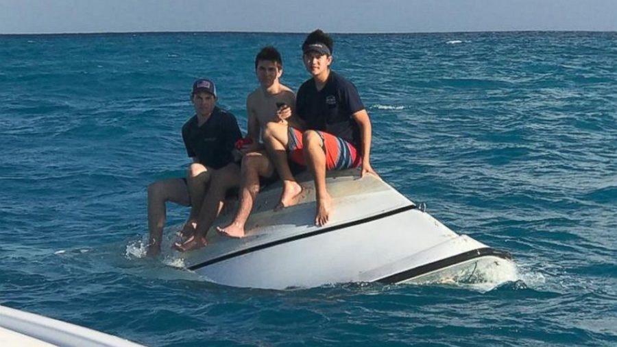 Zack Sowder, left, Jacob Sowder and Brent Shishido, right, sit on a capsized vessel offshore of Little Torch Key in the Florida Keys. 