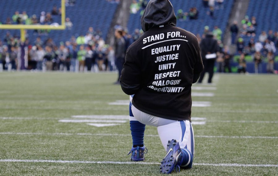 Above, an Indianapolis Colts player Kneels while stretching to display the team message and unity in which their team is trying to showcase.