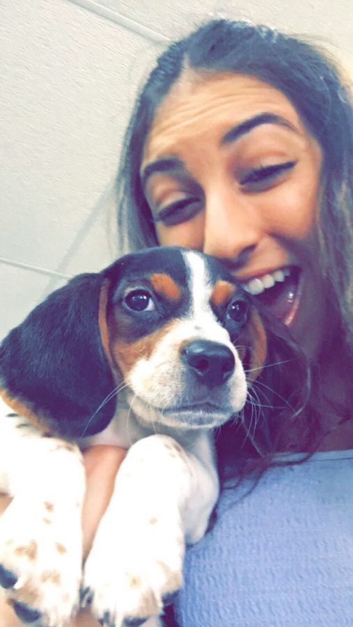 Dani Mallat takes a selfie with a puppy, grinning from ear to ear. 