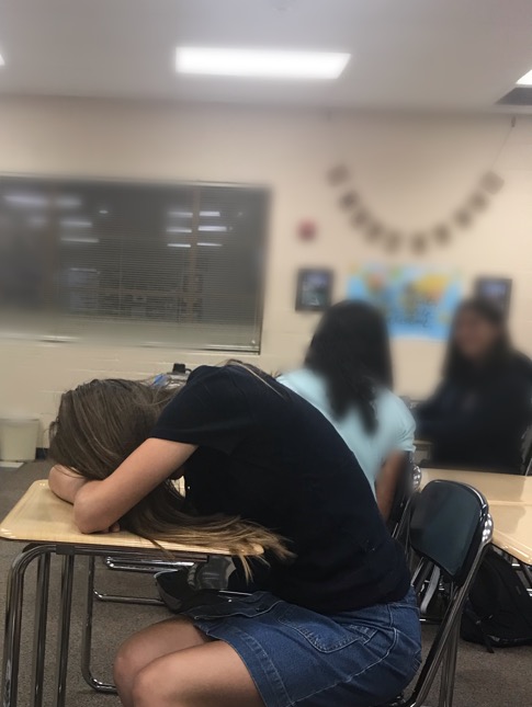 A student sleeping in class after not receiving enough sleep the night before. 
