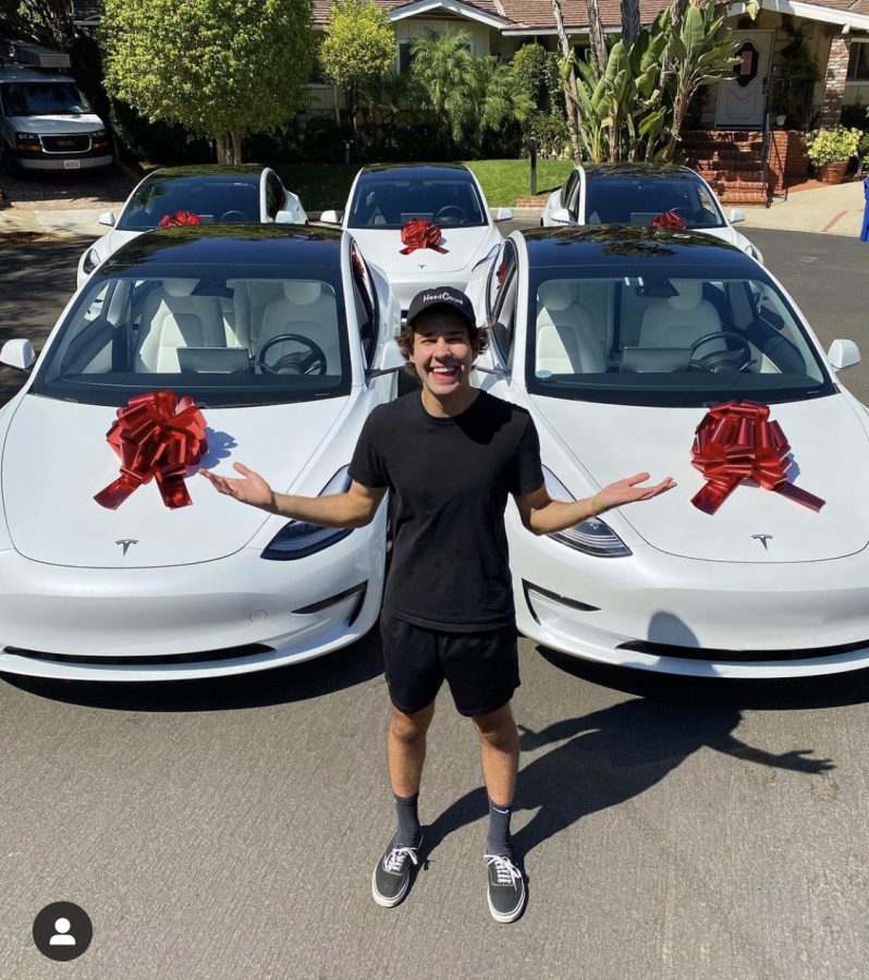 David Dobrik poses in front of 5 Teslas that were awarded to 5 lucky voters.