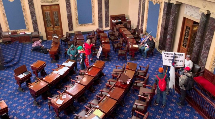 Unattended protesters walk throughout the Capitol building, holding signs and wearing clothing that advocate their support of President Trump. 