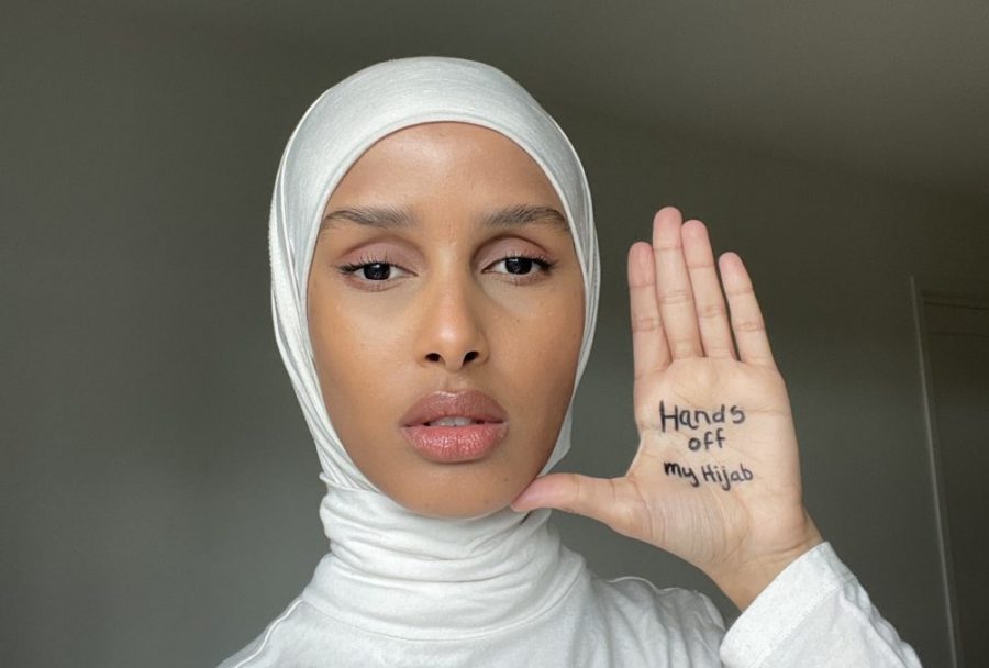 An image of Rawdah Mohamed, wearing a hijab, holding up her hand with the saying “Hands off my hijab”.