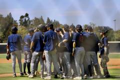 The Yorba Linda Varsity Baseball team in a huddle before the game starts against Aliso Niguel 