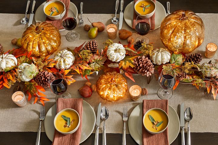 Fall decorations line this Thanksgiving table to bring a comforting atmosphere to the Thanksgiving feast