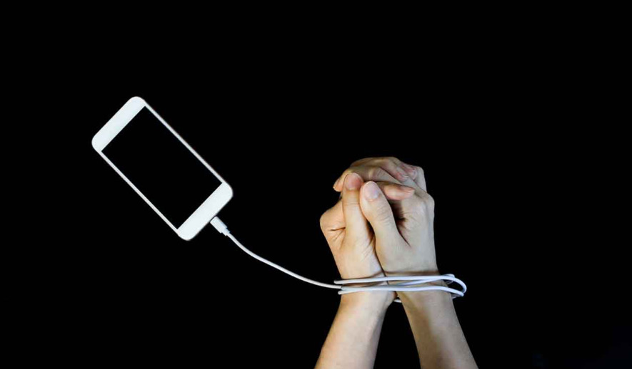 Hands being help captive by the addiction of cellphones. 