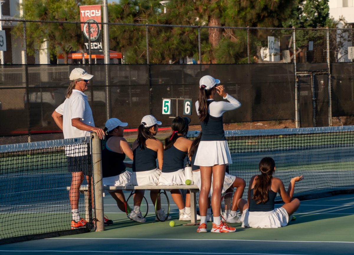 From left to right, Coach Tony Johnson (Staff), Hailee Kim (10), Gabriella Wong (10), Julia Thein (10), Melody Sutanto (10), Abby Ro (9), and Zaara Solorzano (10) observing a game in play against Troy High School.