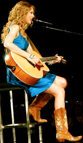 Taylor Swift performing at a concert with her lucky number thirteen written on her hand.