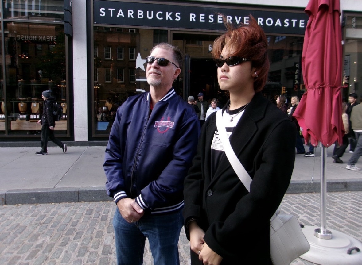 From left to right, Mr. Cadra (S) and Eric Gao (11) stand together while wearing their sunglasses.