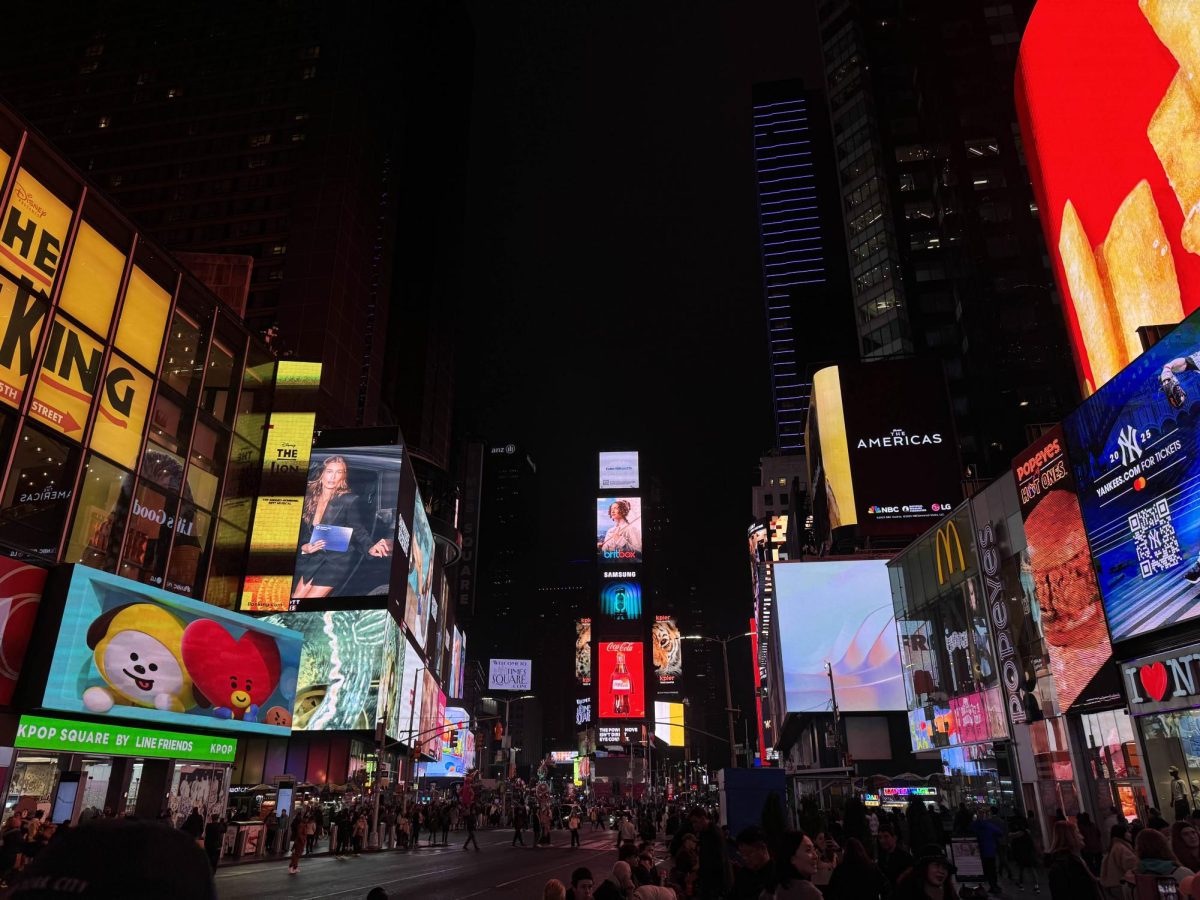 New Yorkers and tourists move through a lit-up Times Square.
