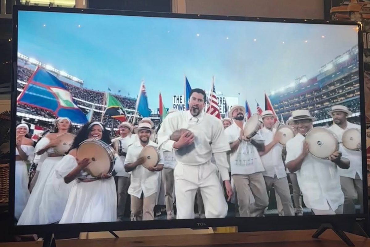 A photo of Bad Bunny Performing at the Super Bowl LX Halftime show, with flags of various American countries behind him. 
