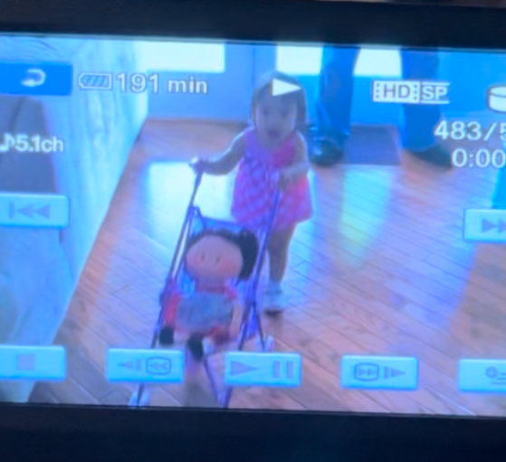 The toddler pushes the baby doll in a stroller, mimicking the behavior she sees adults do every day.