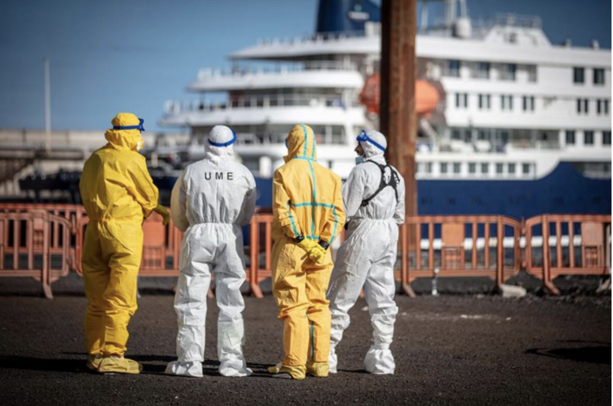 Inspectors standing outside the MV Hondius cruise in protective gear. 
